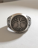 Front view of the Silver Yggdrasil Ring showcasing the intricate Tree of Life design on its face, set on a white surface.
