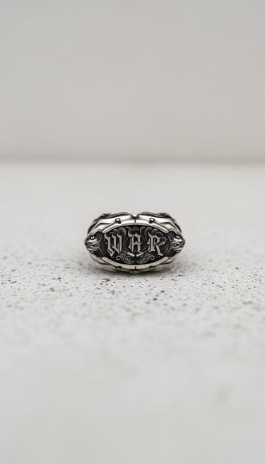 Handcrafted Silver War Ring featuring 'WAR' in a bold gothic font, displayed front-on against a textured light background.