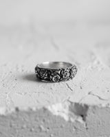 Black and white photo of the sterling silver rose ring, highlighting the oxidized finish and deep petal details on a white surface.