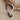 Close-up of minimalist chevron band ring resting on natural stone, highlighting the smooth curved edges and oxidized detail.