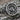 Close-up of silver Gnostic ring featuring Abraxas figure with serpent legs and shield on rustic wooden surface