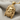 Close-up angled shot of the luxury 14K gold vermeil Zeus pendant resting elegantly on a textured grey fabric background