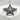 Detailed close-up of oxidized silver nautical star ring displaying chevron textures resting on a concrete surface