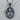 Close-up of the oxidized silver Virgin Mary pendant resting on a textured wooden surface highlighting intricate details