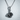 Rose Thorn Pendant, oxidized, front view against wall
