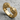 Macro view of intricately carved double lion ring resting on a textured grey stone surface highlighting the mane