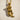 Close-up of the beautiful little mermaid pendant lying flat on a textured surface highlighting the rich gold finish.