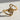 Close-up of golden treble clef ring showing intricate curved metalwork resting on a textured stone surface