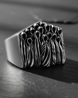 Sterling silver ghost ring in an oxidized finish, close-up showing the haunting, hollow-headed figures on a dark background.