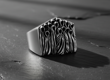 Sterling silver ghost ring in an oxidized finish, close-up showing the haunting, hollow-headed figures on a dark background.