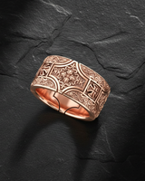Angled view of wide band silver ring featuring deep relief carving of iron cross and acanthus leaves