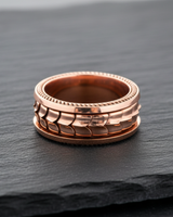 Rose gold plated silver dragon scale ring with rope edge detailing on dark slate background