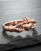 Rose gold plated 925 sterling silver Claddagh ring featuring hands heart and crown displayed on dark slate background