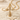 Close-up of sparkling infinity cross pendant resting beautifully on white sand surrounded by small seashells.