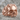 Baroque Scroll Skull Ring in rose gold, front view on stone surface