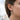 Side profile view of a woman wearing the oxidized silver crucifix cross huggie earring
