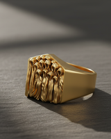 Statement ghost ring in 14k gold vermeil, featuring sculpted spectral figures, resting on a textured grey stone surface.