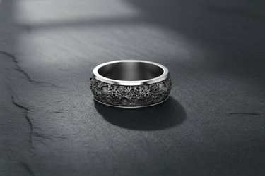 Silver lunar crater ring with oxidized finish and rugged moon texture displayed on slate surface