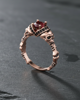 Rose gold plated silver skull engagement ring with red cushion cut gemstone and black accents