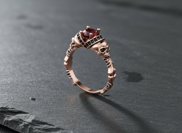 Rose gold plated silver skull engagement ring with red cushion cut gemstone and black accents