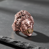 Rose gold plated Silver Justice Ring with blindfolded goddess design and dollar sign gag, resting on a black slate stone.