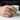Lifestyle view of a man wearing an oxidized silver biomechanical skull ring on hand holding white ceramic cup