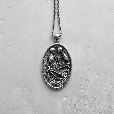 Front view of silver memento mori necklace with kissing skeletons design on a light concrete background