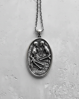 Front view of handcrafted silver skeleton pendant with detailed relief work on textured background for gothic style