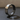 Modern geometric silver ring with oxidized matte segments and a polished accent link, standing on a dark slate surface.