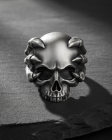 Front view of 925 sterling silver skull ring featuring skeletal claws gripping the cranium on textured dark background