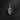 Silver skeleton hand pendant with middle finger gesture, top-down view on a dark, textured slate background.