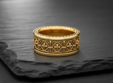 Gold-plated version of the Fleur-de-lis Cross Ring, showing the intricate royal pattern and polished band on a piece of stone.