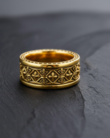 Close-up of gold fleur de lis ring band with intricate medieval design and beaded edges