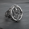 Angled view of silver Jesus ring showing detailed face relief and ornate floral border on dark stone background