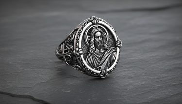 Angled view of silver Jesus ring showing detailed face relief and ornate floral border on dark stone background