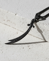 Black rhodium plated 925 sterling silver Zulfiqar sword necklace on textured stone background