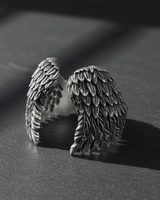 High angle view of handcrafted silver wings ring displaying curved band and realistic feather metalwork details