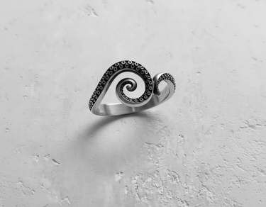 925 sterling silver octopus tentacle ring with spiral design and oxidized suction cups on textured white background