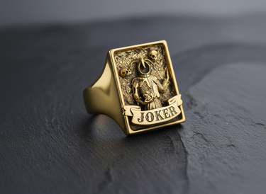 Angled view of gold vermeil Joker ring showing textured background and skull motifs on rectangular signet face