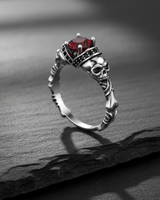 925 sterling silver skull engagement ring featuring a red gemstone and intricate bone band design on dark background