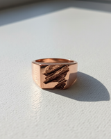 Rose gold plated silver rift signet ring featuring a deep textured gouge on a clean white surface