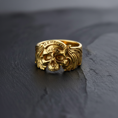 All-gold version of the Memento Mori skull and wings ring, displaying its polished finish and engraved lettering on the banner.