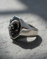Side profile of handcrafted silver ram ring showing polished band thickness and raised relief design on stone