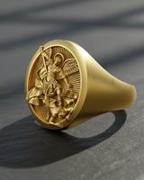 A gold-plated St Michael Ring with detailed relief of the Archangel holding scales and a spear, casting a long shadow.