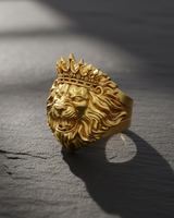 Angled view of gold plated lion ring variant displaying royal design and crown texture on textured surface