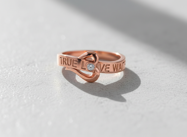 Rose gold plated True Love Waits ring with heart knot and crystal accent on white surface