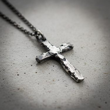 Close-up of handcrafted 925 sterling silver rustic cross pendant with hammered texture on grey background