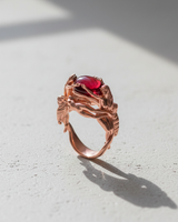 Rose gold variant of the mythology inspired Three Graces ring with central red cabochon