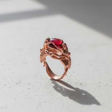 Rose gold variant of the mythology inspired Three Graces ring with central red cabochon