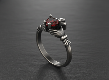Dark oxidized silver Claddagh ring with detailed crown and vibrant red gemstone on textured slate